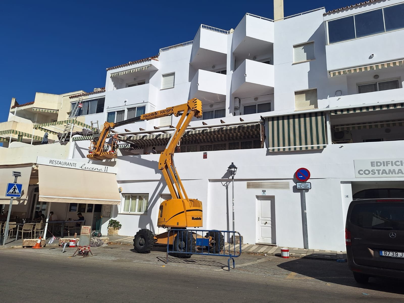 Trabajo de pintura en fachada blanca con plataforma elevadora en edificio Costamar