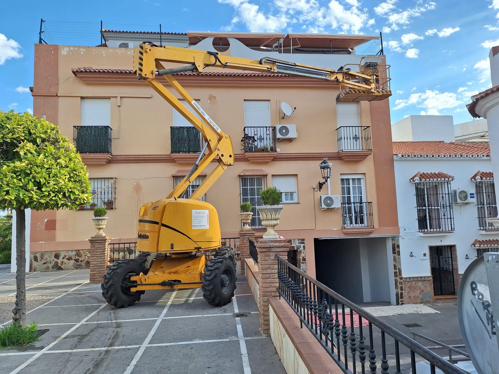 Plataforma elevadora trabajando en una vivienda amarilla