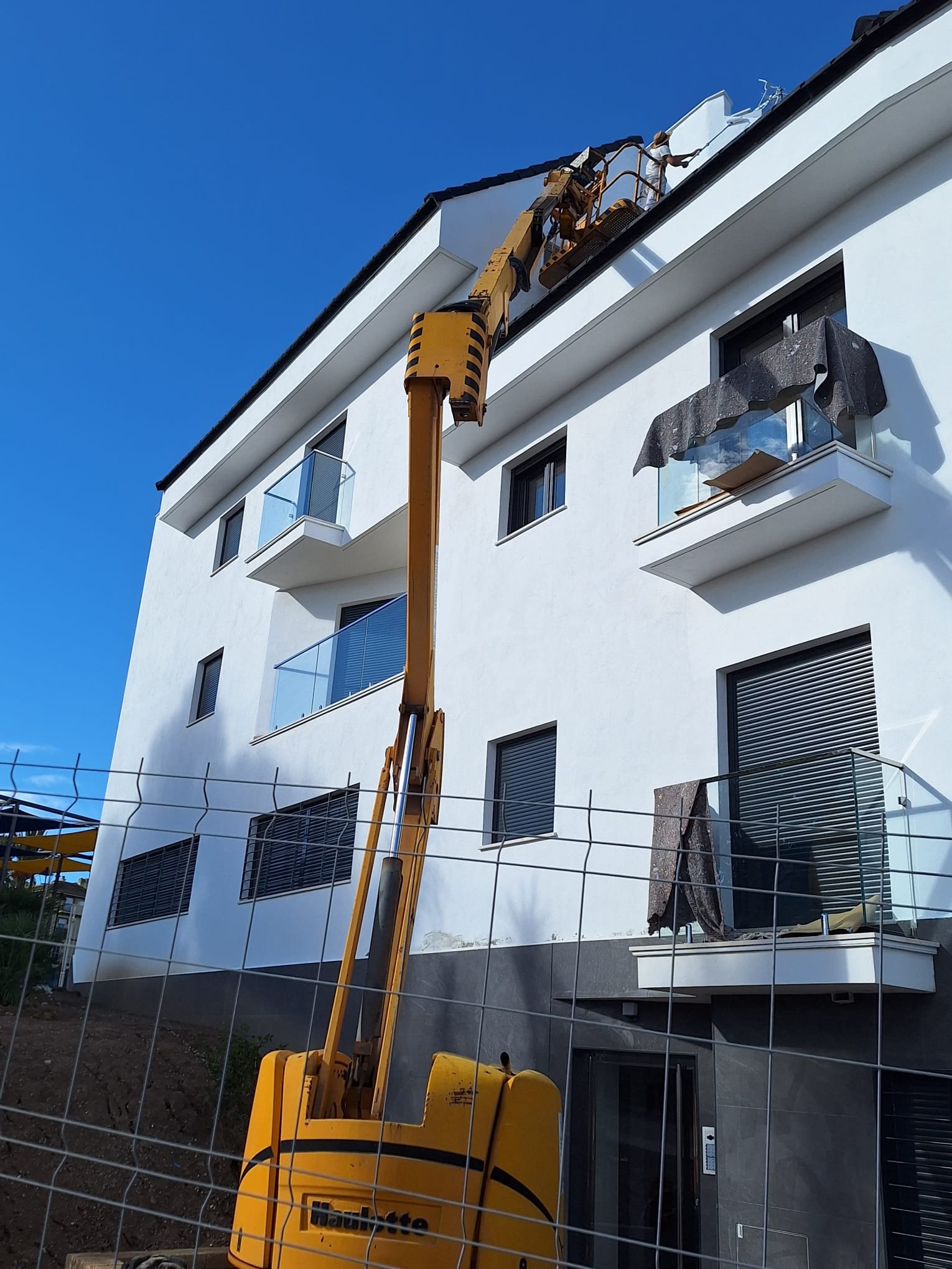Fachada blanca rehabilitada con plataforma elevadora